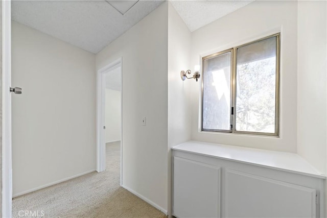 corridor with a textured ceiling and light colored carpet