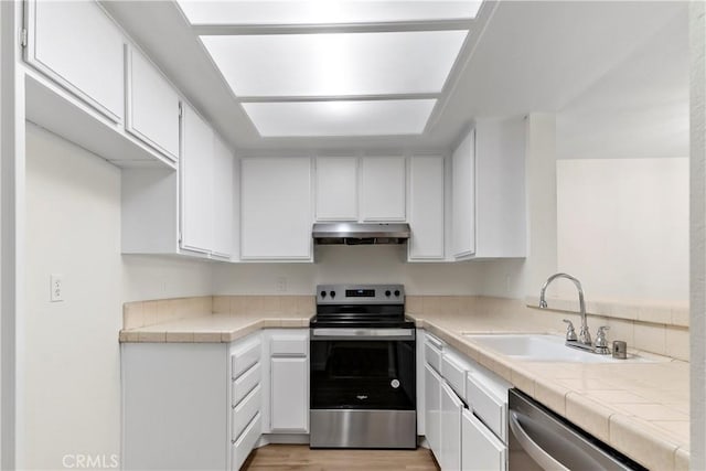 kitchen with tile counters, sink, white cabinets, and stainless steel appliances