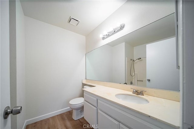 bathroom featuring toilet, a shower, hardwood / wood-style flooring, and vanity