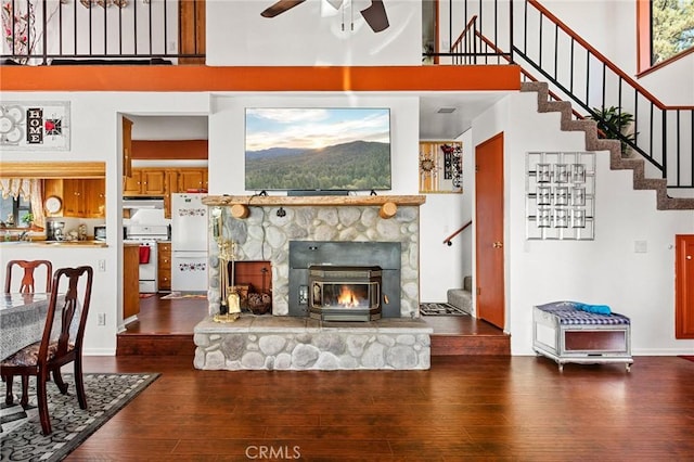 living room with a high ceiling, ceiling fan, and wood-type flooring