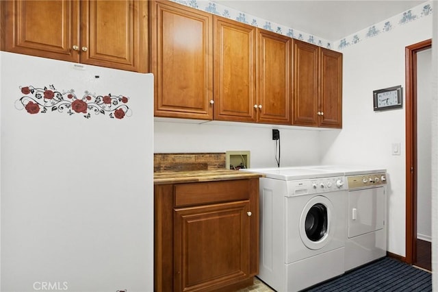 clothes washing area with washer and dryer and cabinets