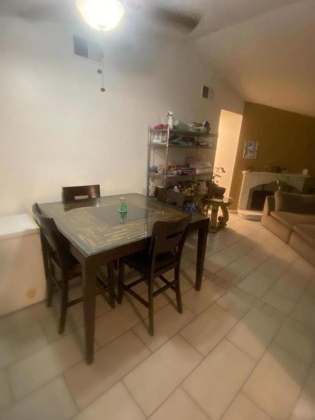 tiled dining room featuring vaulted ceiling