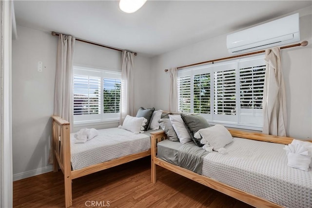 bedroom featuring multiple windows, hardwood / wood-style flooring, and a wall unit AC