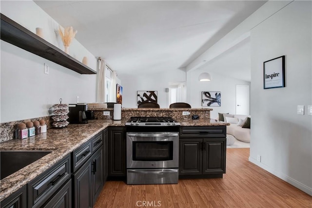 kitchen with gas range, dark stone countertops, and light hardwood / wood-style flooring