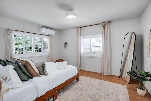 bedroom featuring a wall mounted air conditioner and light wood-type flooring