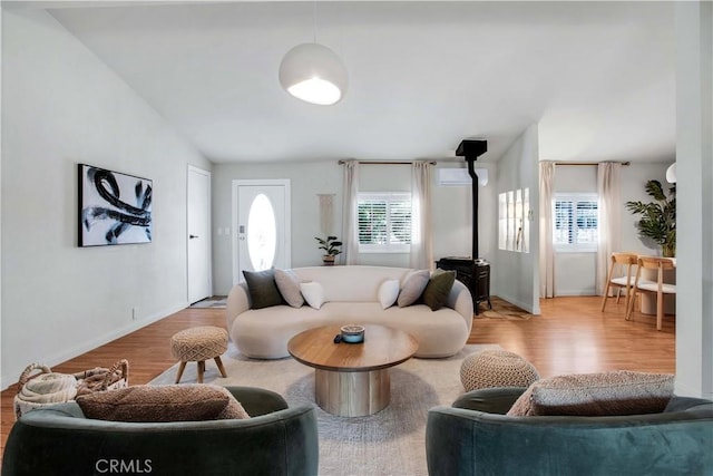 living room featuring light hardwood / wood-style flooring, a wood stove, and vaulted ceiling