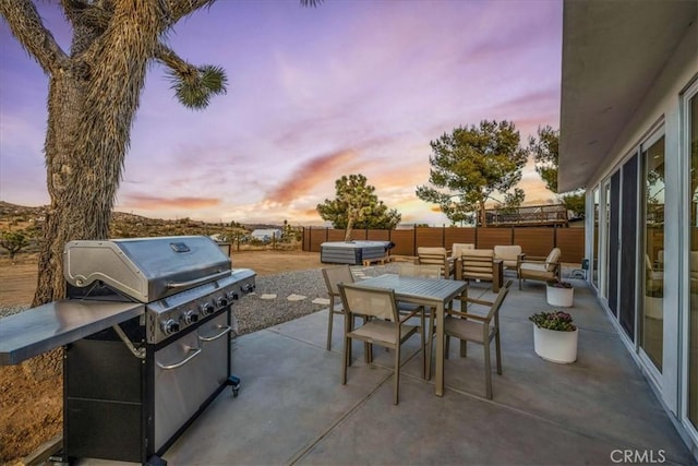 patio terrace at dusk featuring grilling area, outdoor lounge area, and a jacuzzi