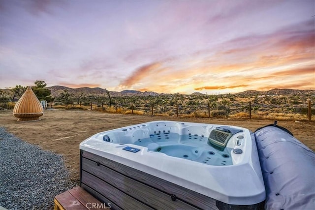 patio terrace at dusk with a mountain view and a hot tub