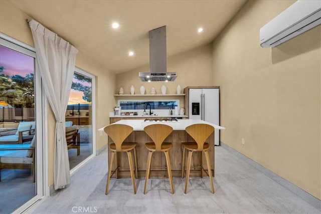 kitchen featuring a wall unit AC, island range hood, high quality fridge, a kitchen bar, and vaulted ceiling