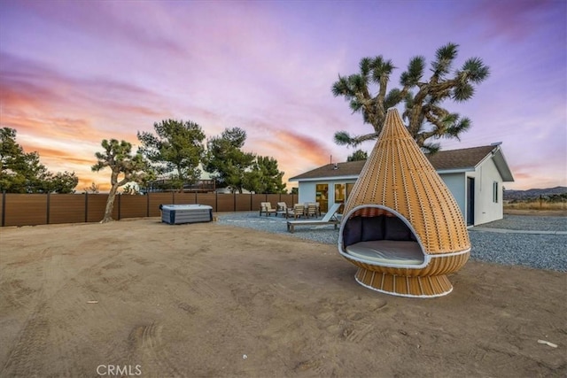 yard at dusk featuring a jacuzzi and a patio