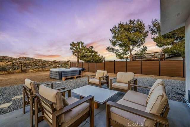 patio terrace at dusk featuring an outdoor living space and a hot tub