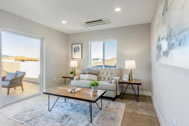 living room with a wall mounted air conditioner and light colored carpet