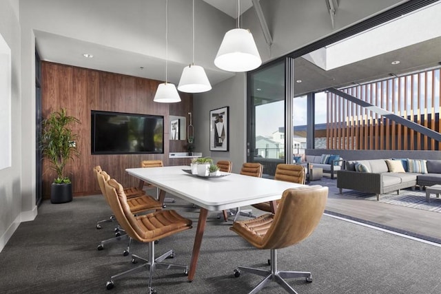 carpeted dining space with wooden walls