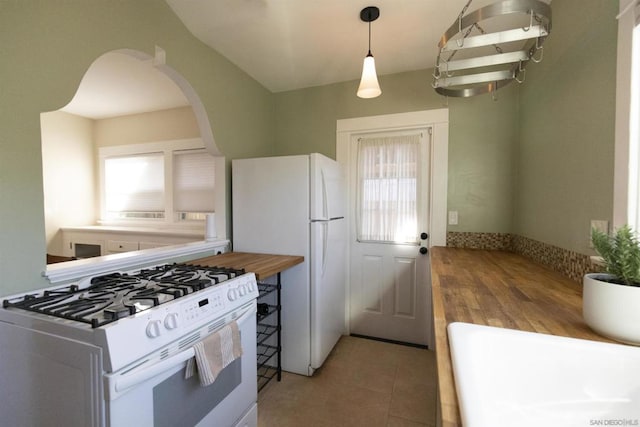 kitchen with wooden counters, white appliances, decorative light fixtures, and tile patterned floors