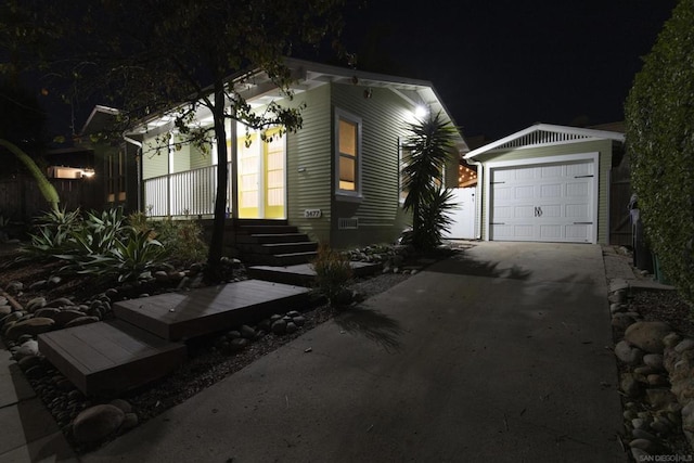 property exterior at night with a garage and an outbuilding