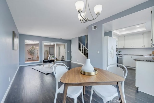 dining space featuring dark hardwood / wood-style flooring, a tray ceiling, and a notable chandelier