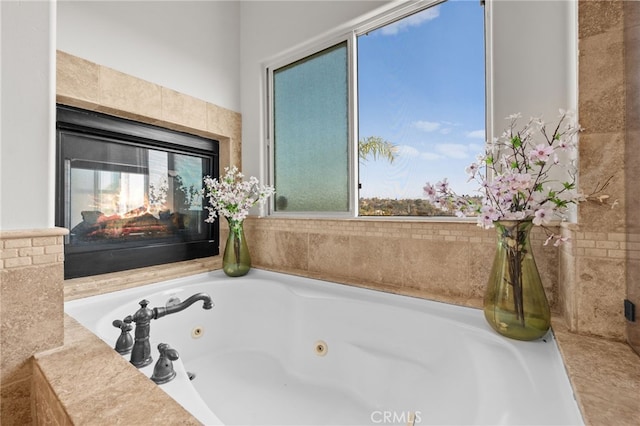 bathroom featuring a multi sided fireplace and tiled tub