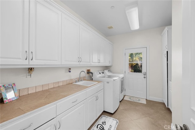 washroom with cabinets, sink, independent washer and dryer, and light tile patterned flooring