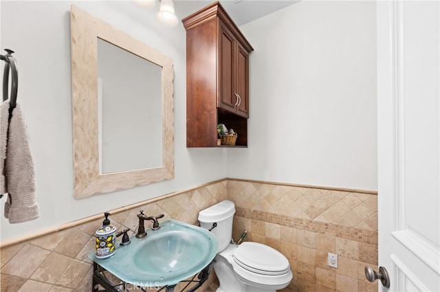 bathroom featuring sink, tile walls, and toilet