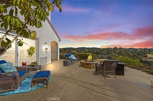 patio terrace at dusk featuring an outdoor fire pit