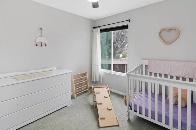 bedroom featuring ceiling fan, a nursery area, and carpet floors