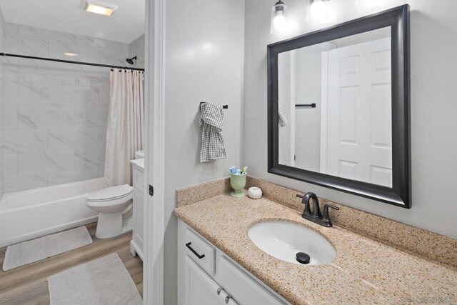 full bathroom with toilet, shower / tub combo, wood-type flooring, and vanity