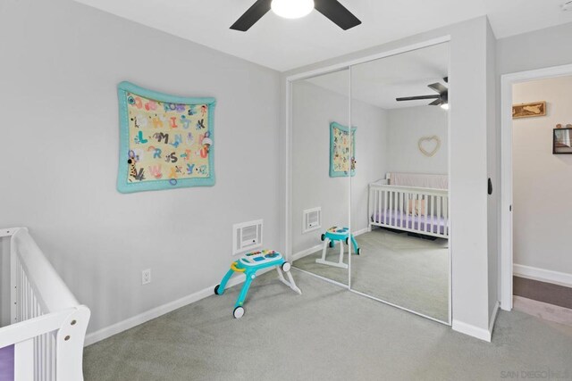 bedroom with ceiling fan, a nursery area, a closet, and carpet flooring