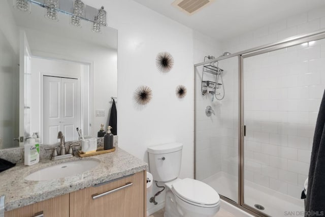 bathroom with toilet, a shower with door, and vanity