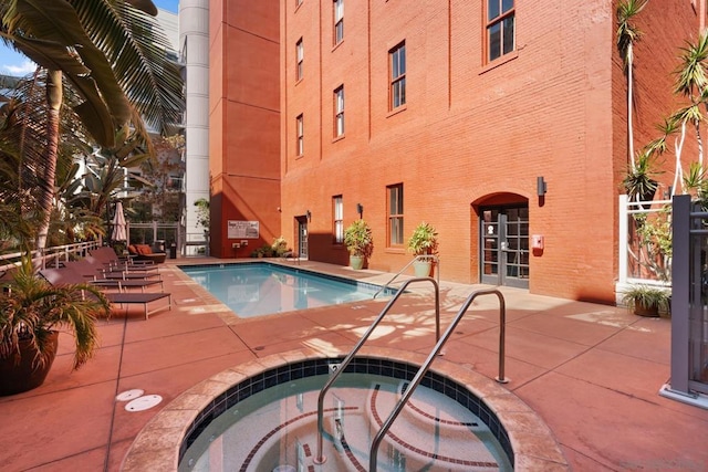 view of pool featuring a hot tub and a patio