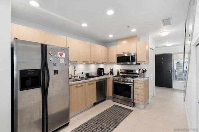 kitchen with light stone countertops, appliances with stainless steel finishes, light brown cabinets, tasteful backsplash, and sink