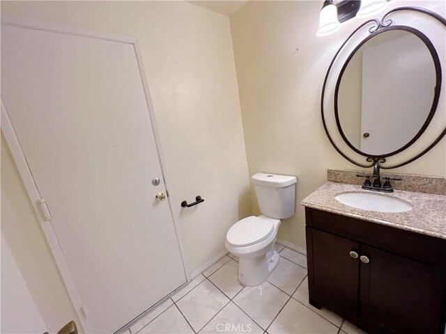 bathroom with toilet, vanity, and tile patterned floors