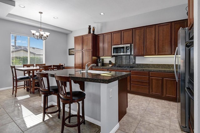 kitchen featuring appliances with stainless steel finishes, decorative light fixtures, a kitchen island with sink, a chandelier, and sink