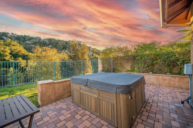 patio terrace at dusk featuring a hot tub