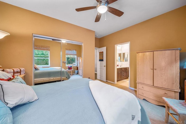 bedroom with ceiling fan, light carpet, and ensuite bath