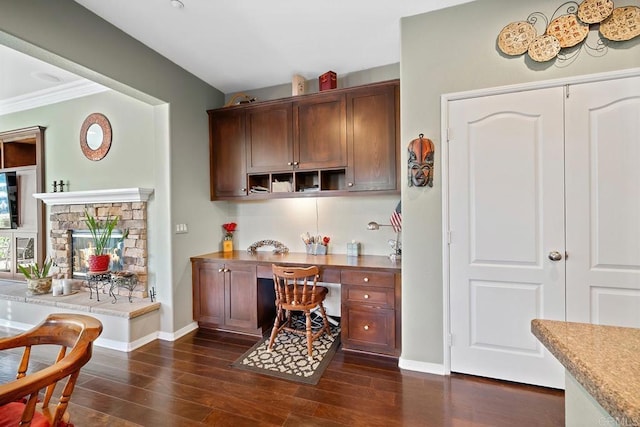 kitchen with dark wood-type flooring, ornamental molding, and a fireplace