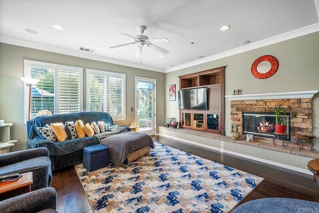 living room featuring dark wood-type flooring, crown molding, a fireplace, and ceiling fan