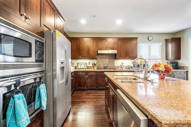 kitchen with stainless steel appliances, dark hardwood / wood-style floors, light stone counters, and sink