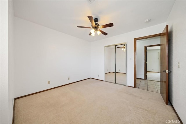 unfurnished bedroom featuring ceiling fan, a closet, and light colored carpet