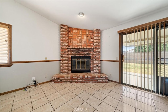 unfurnished living room featuring a fireplace, lofted ceiling, and light tile patterned flooring