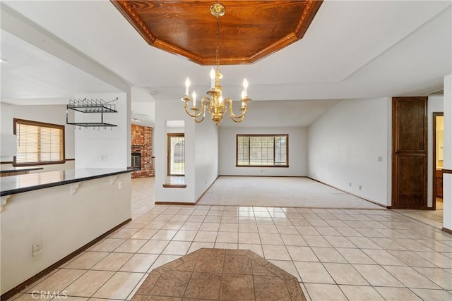 unfurnished dining area featuring plenty of natural light, light tile patterned flooring, a tray ceiling, and a chandelier