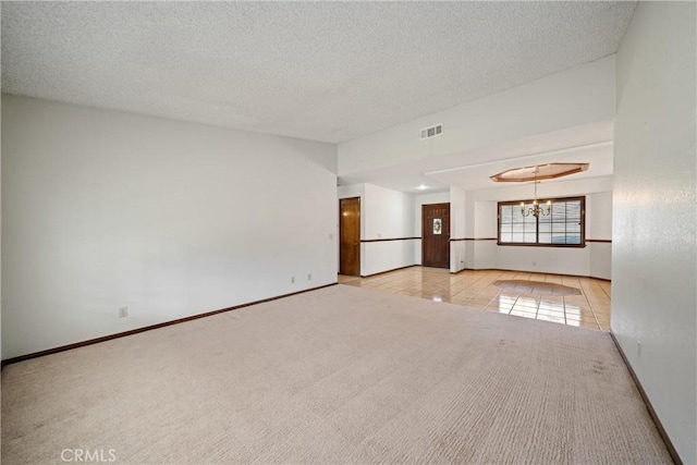 empty room featuring a textured ceiling, light tile patterned floors, and a chandelier