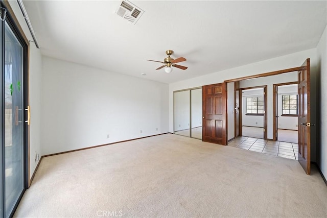 unfurnished bedroom featuring ceiling fan, two closets, and light carpet