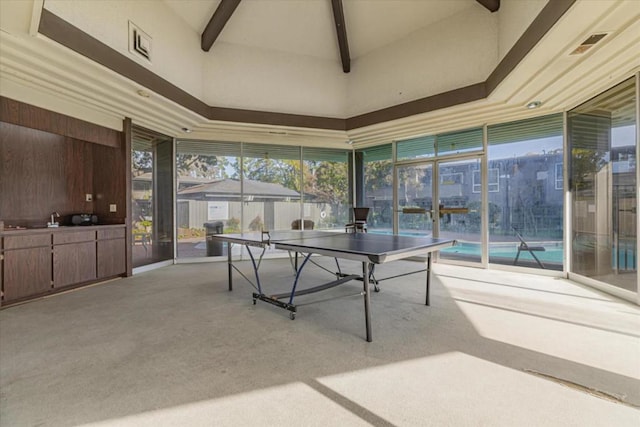 rec room with light carpet and a high ceiling