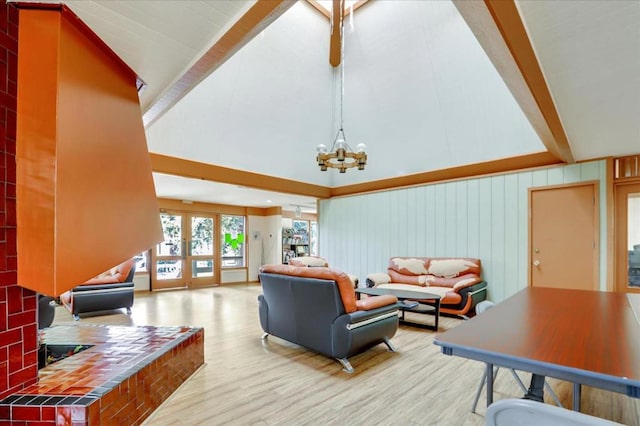 living room with light hardwood / wood-style floors, wooden walls, a notable chandelier, french doors, and high vaulted ceiling