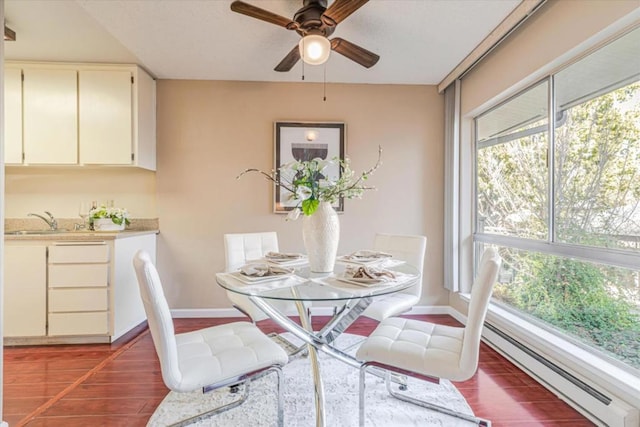 dining space with ceiling fan, plenty of natural light, a baseboard radiator, and sink