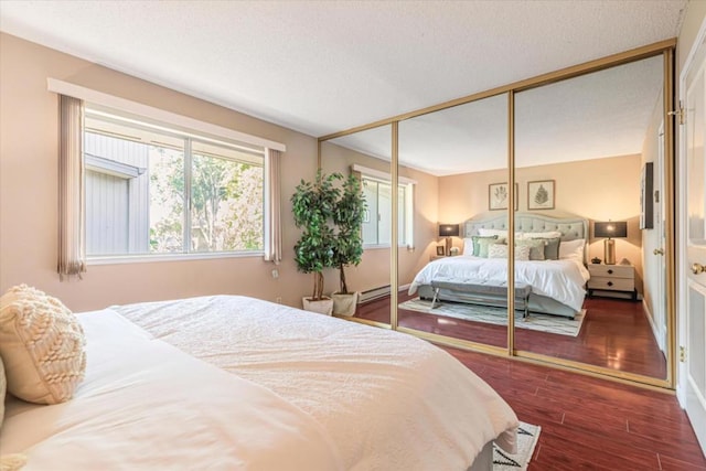 bedroom featuring a baseboard heating unit, a closet, and dark hardwood / wood-style flooring