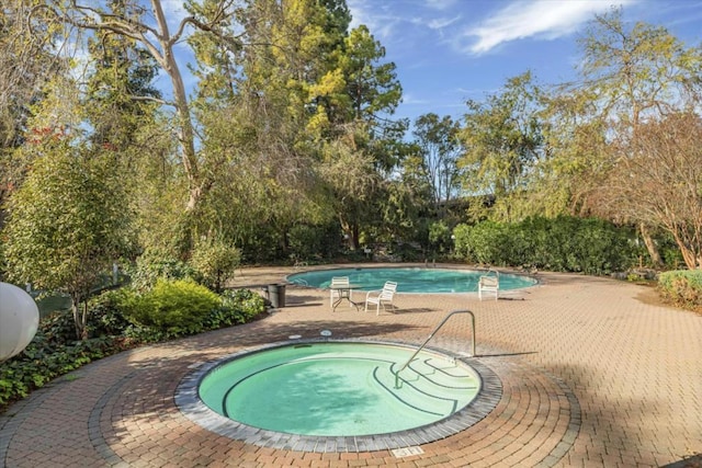 view of swimming pool featuring a hot tub and a patio