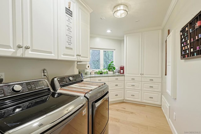 laundry room featuring cabinets, separate washer and dryer, ornamental molding, and light hardwood / wood-style floors