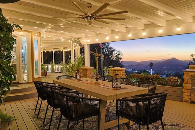 deck at dusk featuring ceiling fan and a mountain view