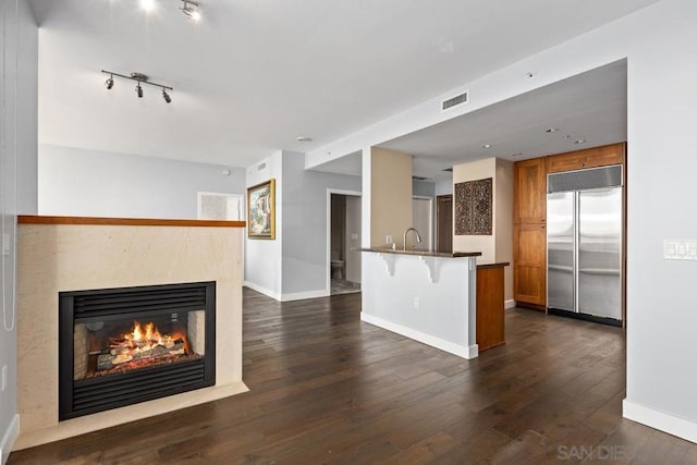 kitchen with a kitchen breakfast bar, built in refrigerator, dark hardwood / wood-style flooring, and sink